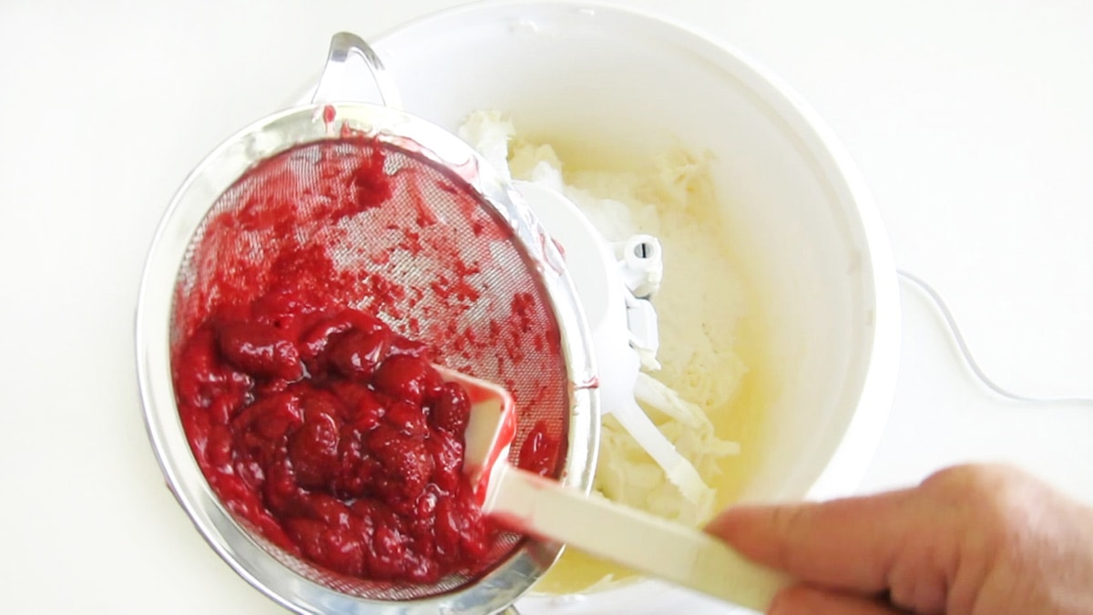 adding the strawberry pie filling to the cream cheese and powdered sugar in the mixing bowl.