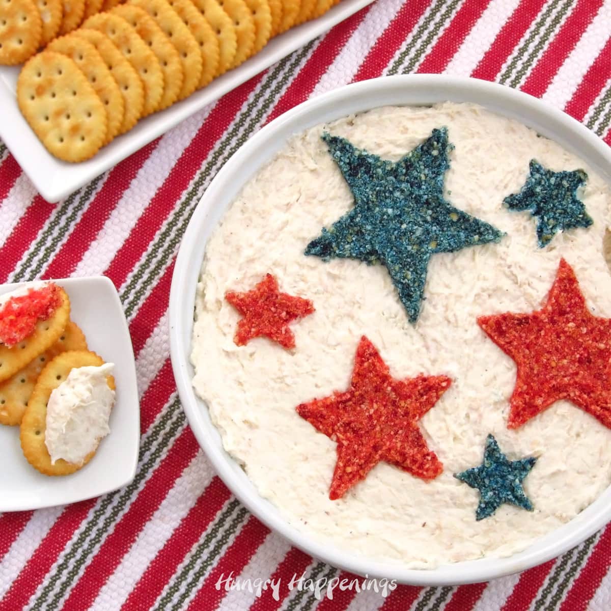 red, white, and blue 4th of July appetizer hot chicken dip served in a round dish with crackers on a patriotic napkin.
