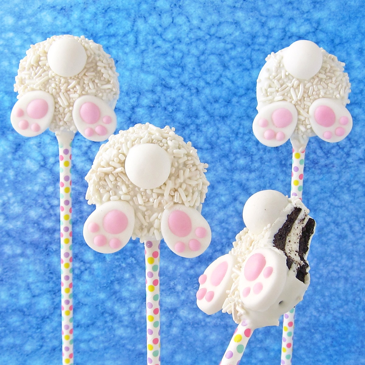 bunny butt cookies made with white chocolate-dipped OREO Cookies, white sprinkles, candy bunny feet and tails.