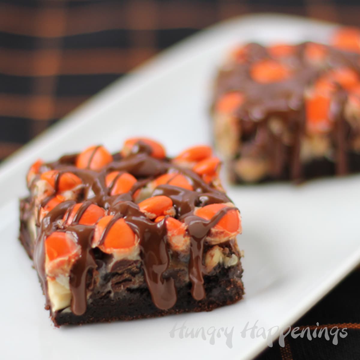 chocolate magic bars with layers of chocolate cookies topped with caramel, peanuts, Reese's Pieces and chocolate peanut butter glaze. 