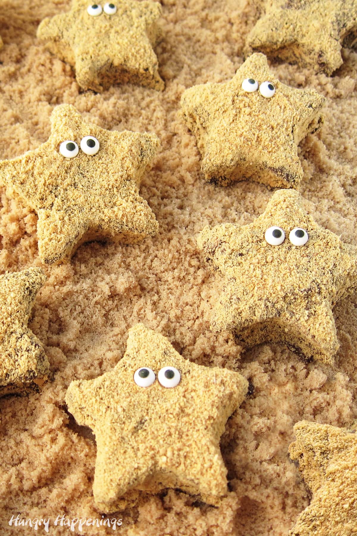 chocolate-dipped marshmallow starfish s'mores arranged on brown sugar sand.