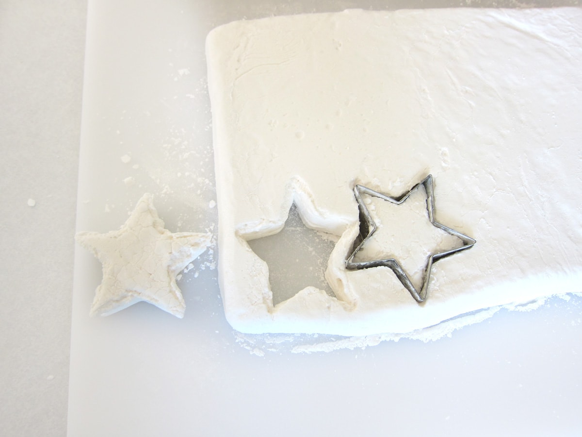 cutting stars out of a sheet of marshmallows using a metal cookie cutter.