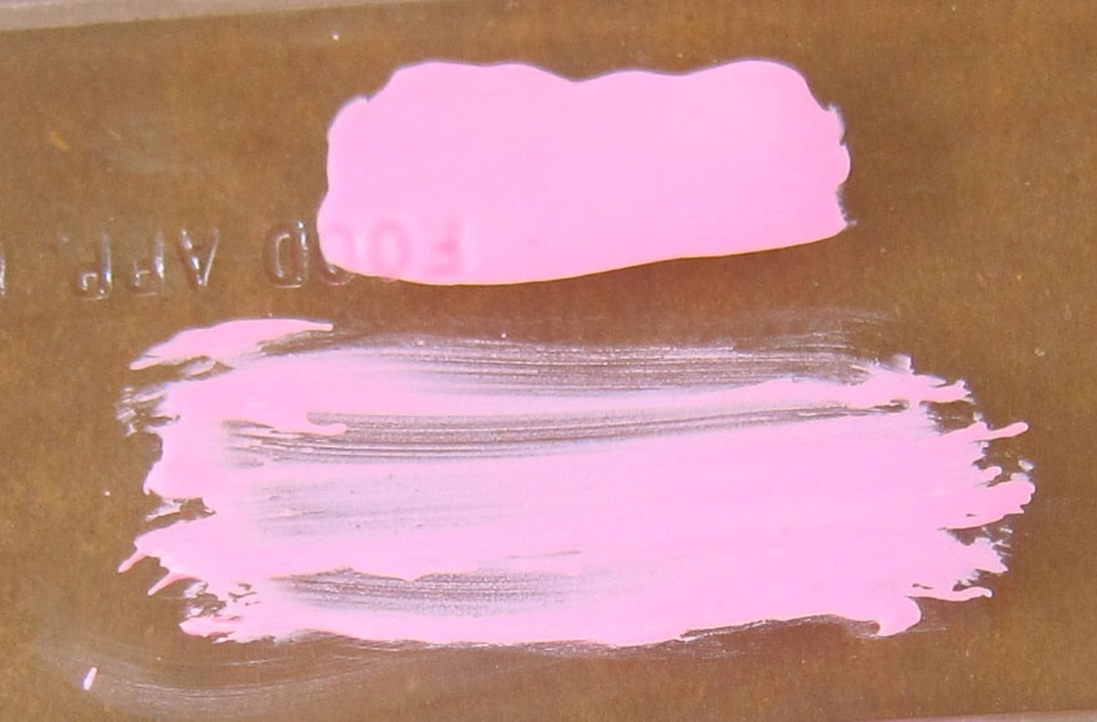 thick opaque pink candy melts that have been dabbed onto a plastic candy mold and see-through pink candy melts that have been brushed onto the mold. 