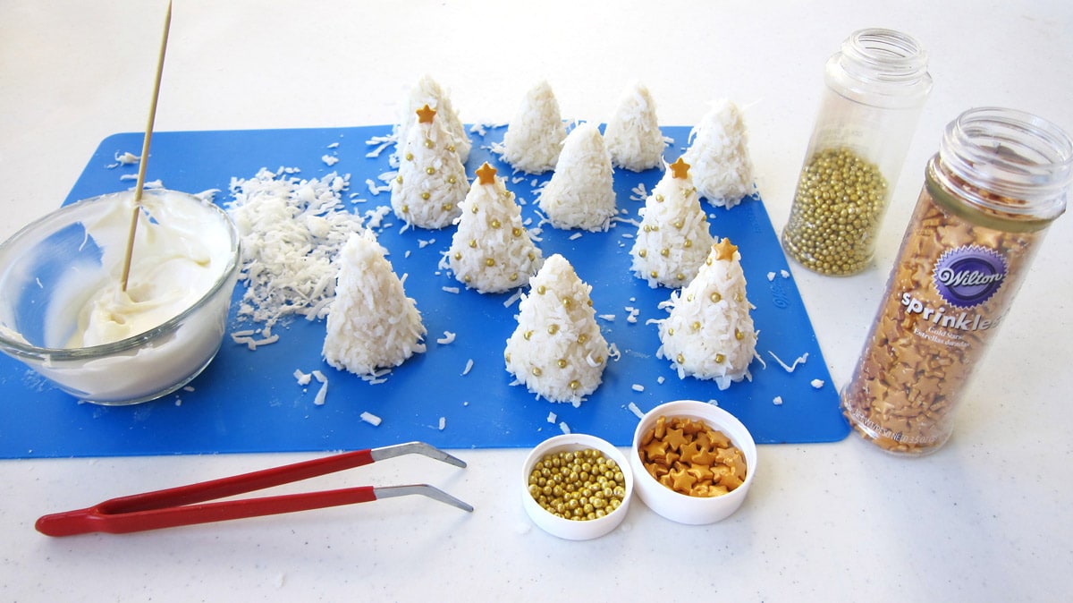 decorate coconut candy Christmas trees with gold drages and star-shaped sprinkles.