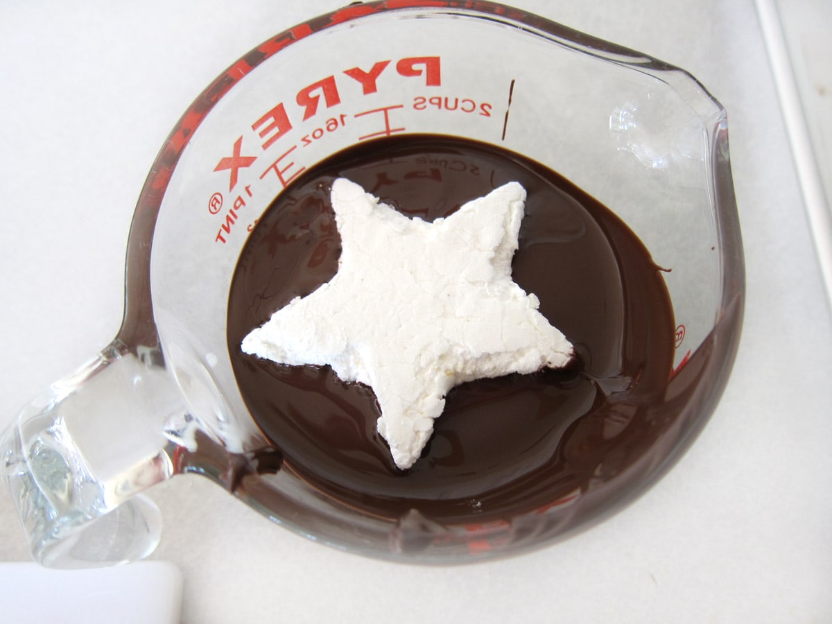 marshmallow star on top of melted chocolate in a measuring cup.