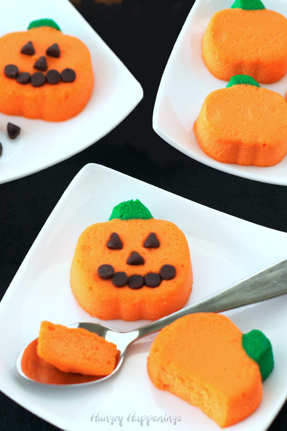 Halloween cheesecake pumpkins mini Jack-O-Lanterns on white square plates.