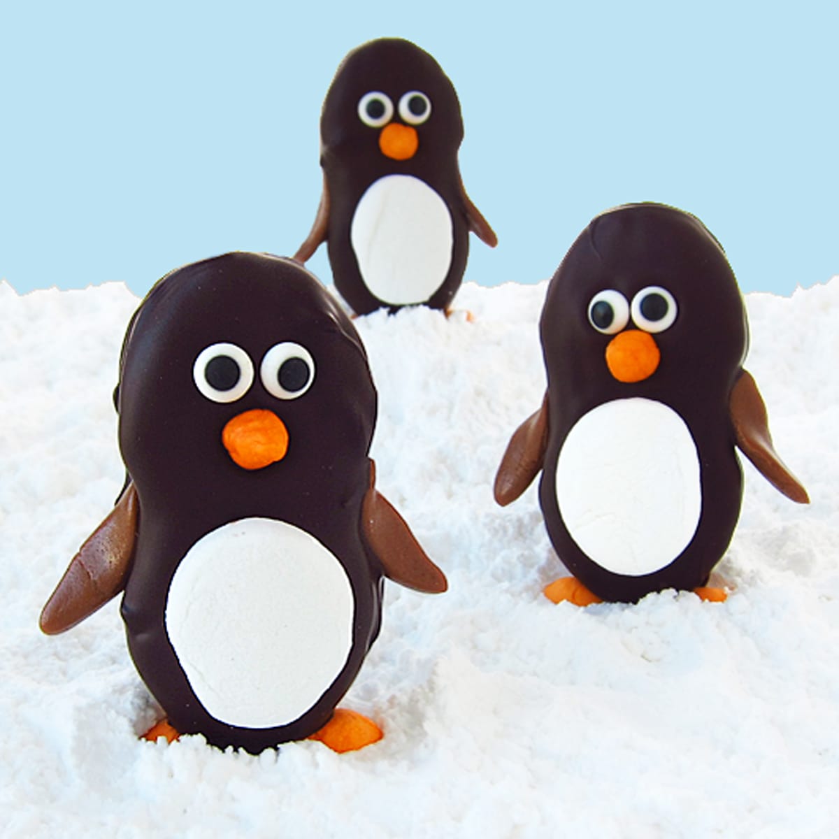 chocolate Nutter Butter penguins on powdered sugar snow with a blue background