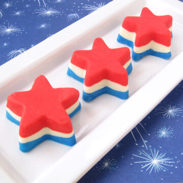red, white, and blue fudge stars on a white plate on top of 4th of July fireworks paper.