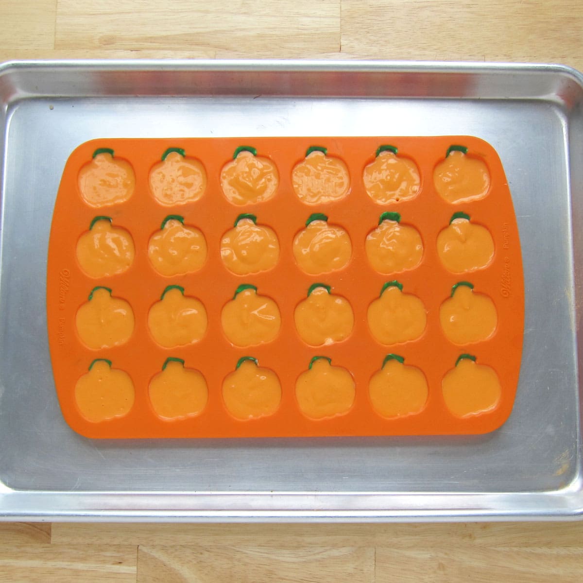 a silicone pumpkin mold filled with colored cheesecake filling.