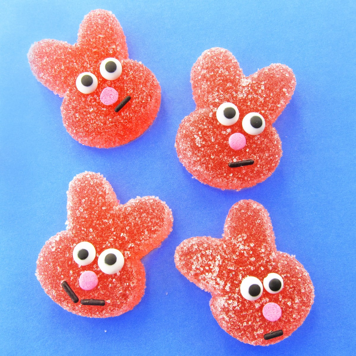 homemade sour gummy bunnies with candy eyes, a pink sprinkle nose, and a black jimmy smile.