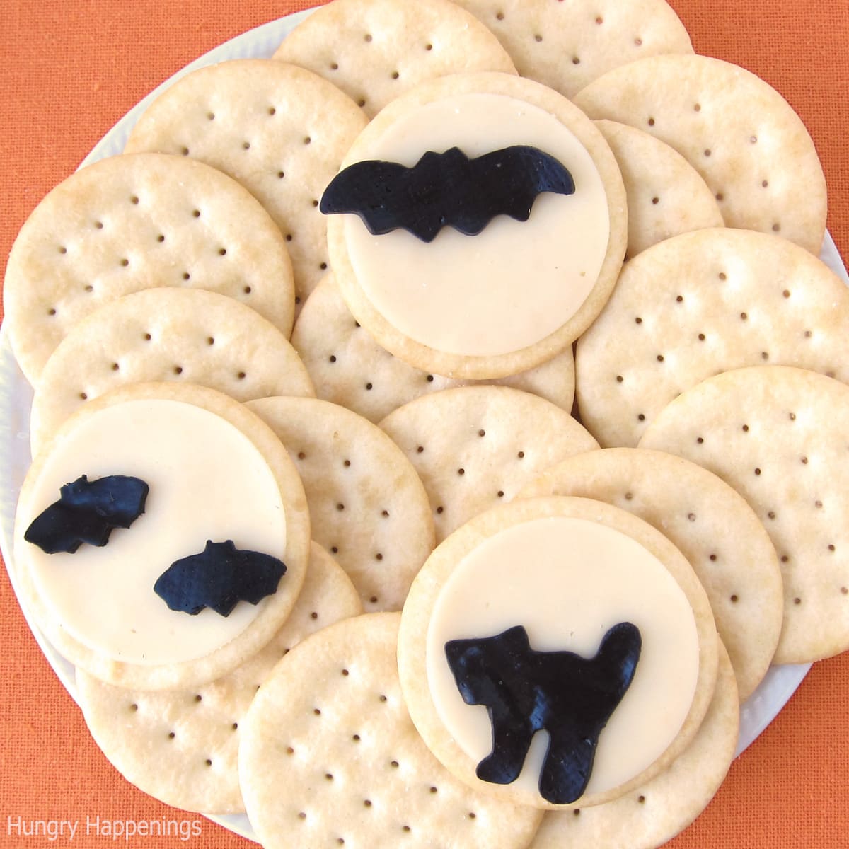 Halloween cheese and crackers topped with white cheese moons and black cheese bats and cats.
