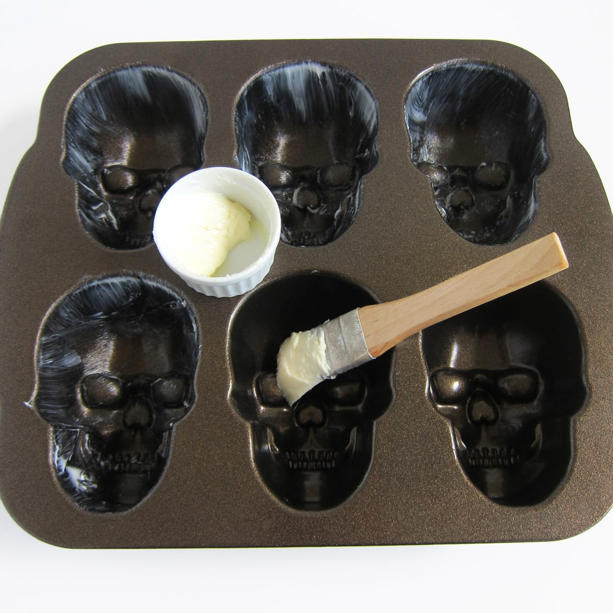 greasing a Nordic Ware skull pan with butter.