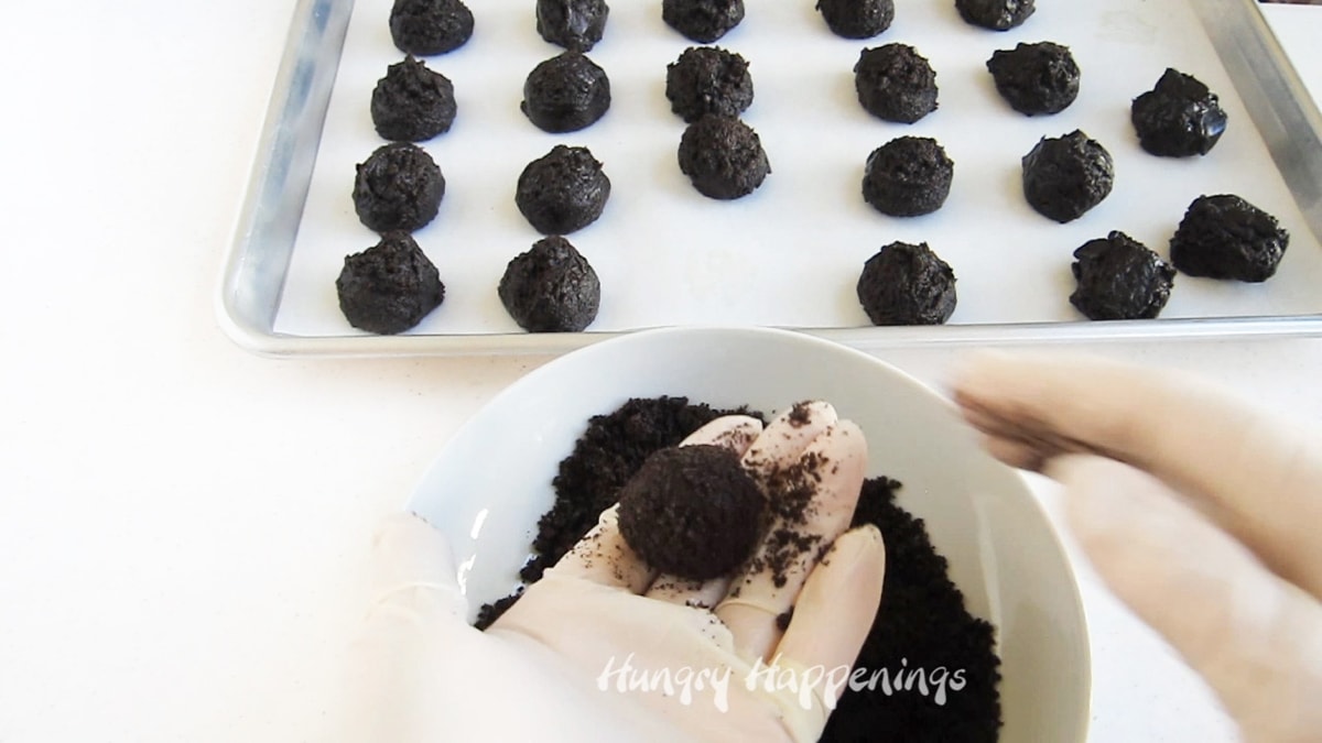 rolling oreo cookie balls in oreo cookie crumbs.