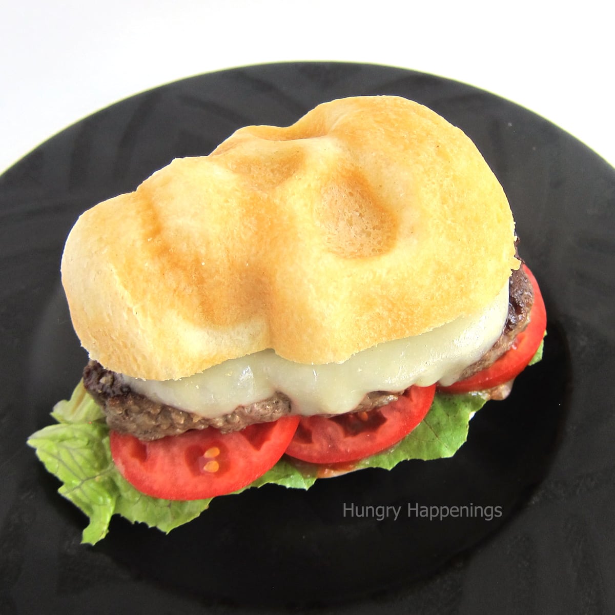 side view of a skull-shaped cheeseburger with lettuce and tomatoes.