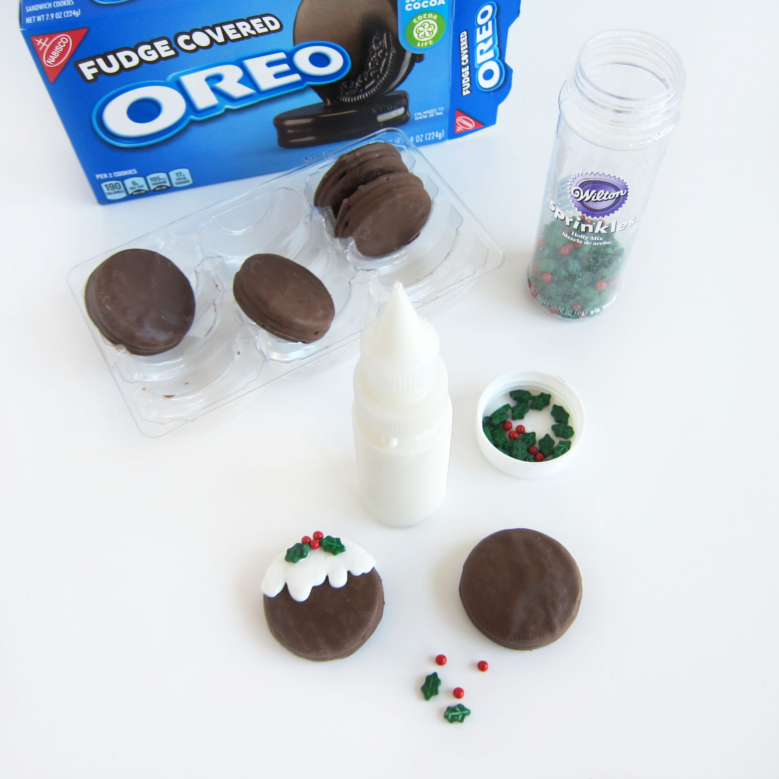 Making Christmas Pudding OREOs using Fudge Covered OREO Cookies, white candy melts, and holly and berries sprinkles.