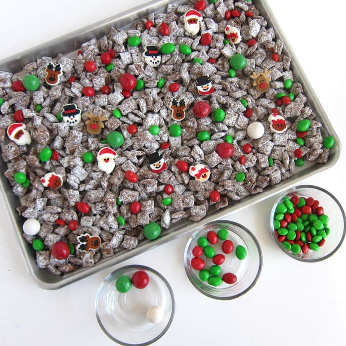 making Christmas puppy chow topped with red and green peanut and plain M&M's, royal icing decorations, and Christmas malted milk balls.