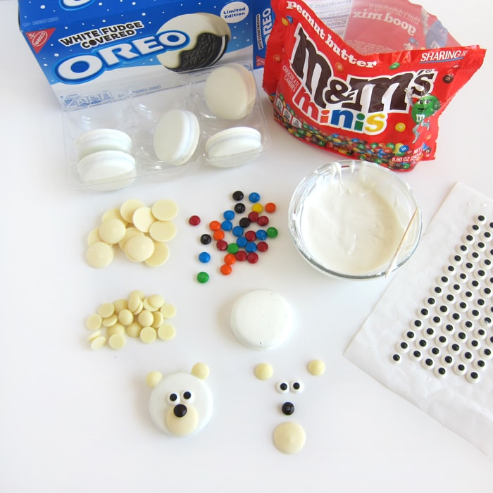 Ingredients to make polar bear OREOs including white fudge covered OREO Cookies, mini M&Ms, white candy melts, white chocolate chips, and candy eyes.