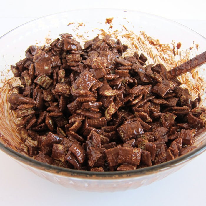 mixing melted chocolate, peanut butter, and butter with Rice Chex Cereal to make puppy chow.