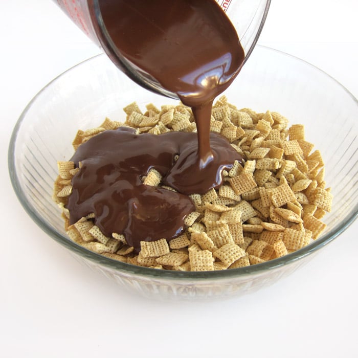 pouring the melted butter, chocolate, and peanut butter over a big bowl of Rice Chex.