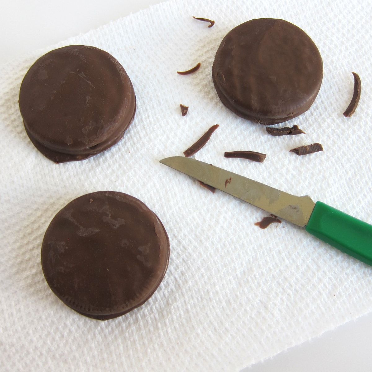 shaving the excess chocolate off the chocolate fudge covered OREOs. 